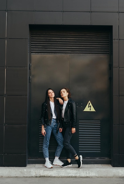 Photo de rue de deux copines sur fond de mur sombre Espace de copie