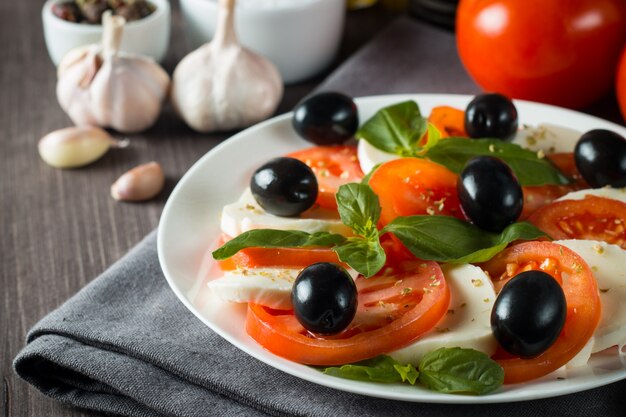 Photo de salade caprese aux tomates, basilic, mozzarella, olives et huile d'olive