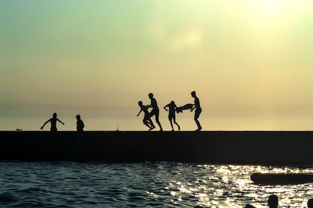 Photo de silhouette de personnes se reposant sur la jetée après le coucher du soleil