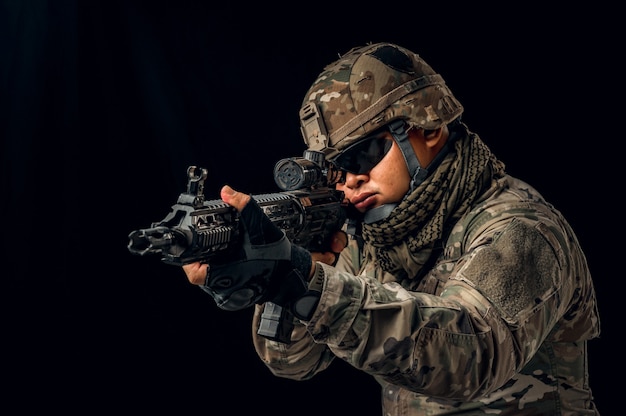 Photo de soldat sur fond noir. Soldat des forces spéciales des États-Unis ou entrepreneurs militaires privés tenant un fusil. Image sur fond noir. concept de soldat, d'armée, de guerre, d'arme et de technologie.