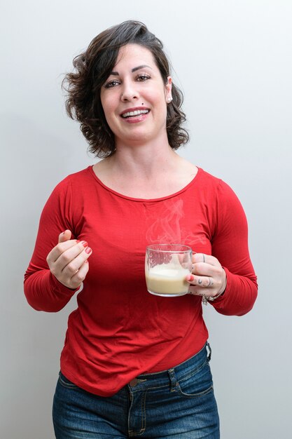 Photo spontanée. Femme brésilienne souriante, tenant une tasse à cappuccino et racontant une histoire amusante.