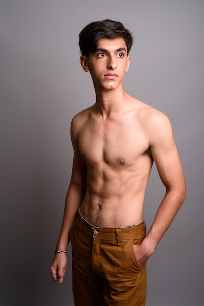 Photo de Studio de beau jeune adolescent persan torse nu sur fond gris