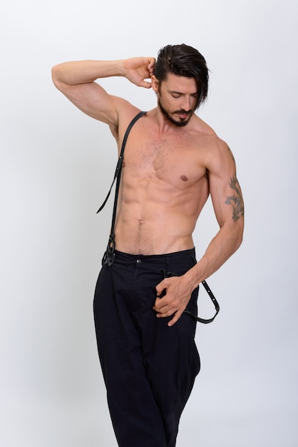 Photo de Studio de bel homme posant avec des bretelles torse nu