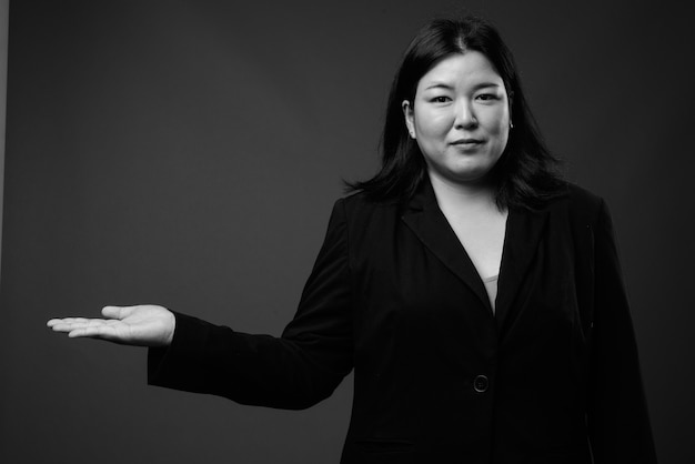 Photo de Studio de belle femme d'affaires asiatique en surpoids sur fond gris en noir et blanc