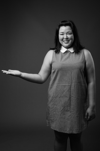 Photo de Studio de belle femme asiatique en surpoids portant une robe sur fond gris en noir et blanc