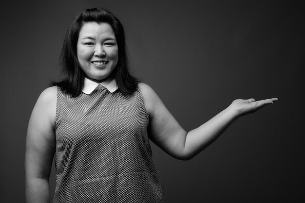 Photo de Studio de belle femme asiatique en surpoids portant une robe sur fond gris en noir et blanc