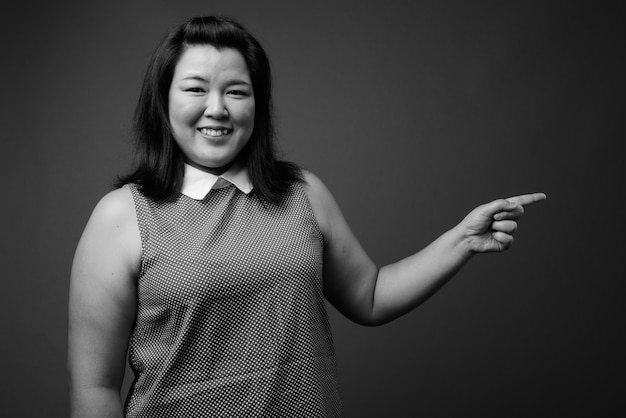 Photo de Studio de belle femme asiatique en surpoids portant une robe sur fond gris en noir et blanc