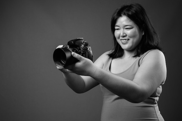 Photo de Studio de belle femme asiatique en surpoids portant une robe sans manches sur fond gris en noir et blanc