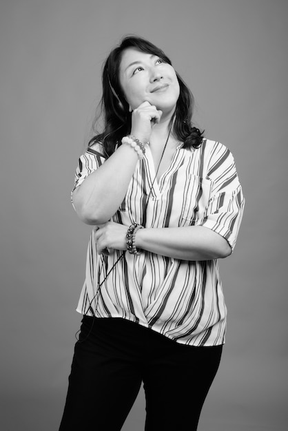 Photo de Studio de belle femme japonaise mature contre gris en noir et blanc