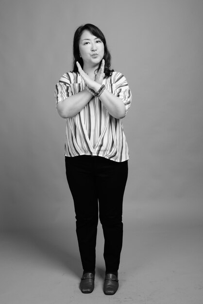 Photo de Studio de belle femme japonaise mature contre gris en noir et blanc