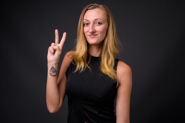 Photo de Studio de belle jeune femme d'affaires aux cheveux blonds raides contre gris