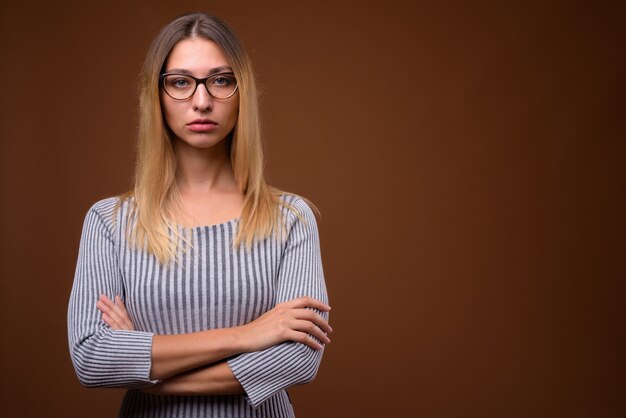 Photo de Studio de belle jeune femme contre le mur marron