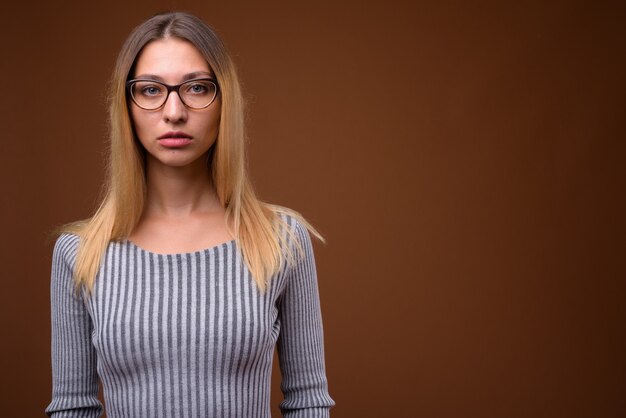 Photo de Studio de belle jeune femme contre le mur marron