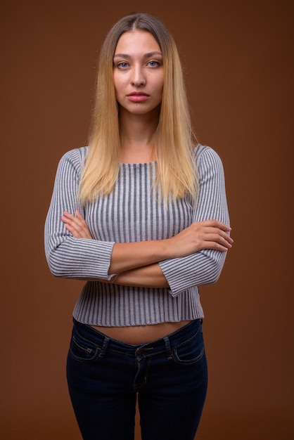 Photo de Studio de belle jeune femme contre le mur marron