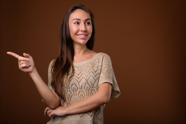 Photo de Studio de belle jeune femme sur fond marron