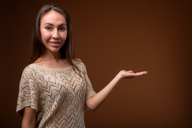 Photo de Studio de belle jeune femme sur fond marron