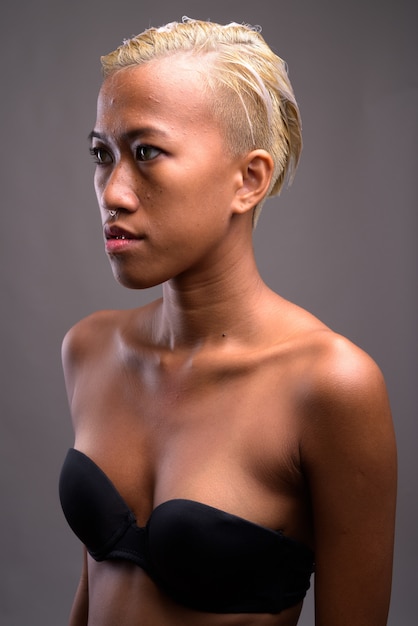 Photo de Studio de belle jeune femme rebelle aux cheveux courts contre gris