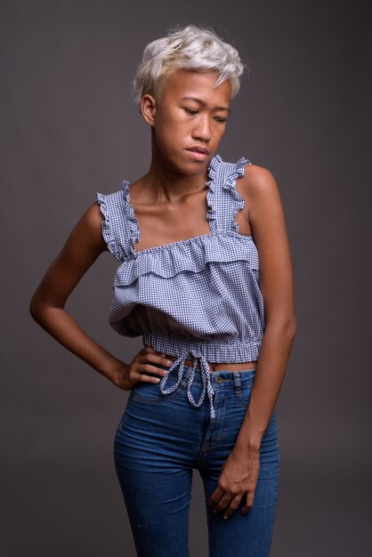 Photo de Studio de belle jeune femme rebelle aux cheveux courts contre gris