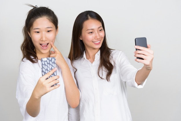 Photo de Studio de deux belles jeunes femmes coréennes comme amis ensemble sur fond blanc