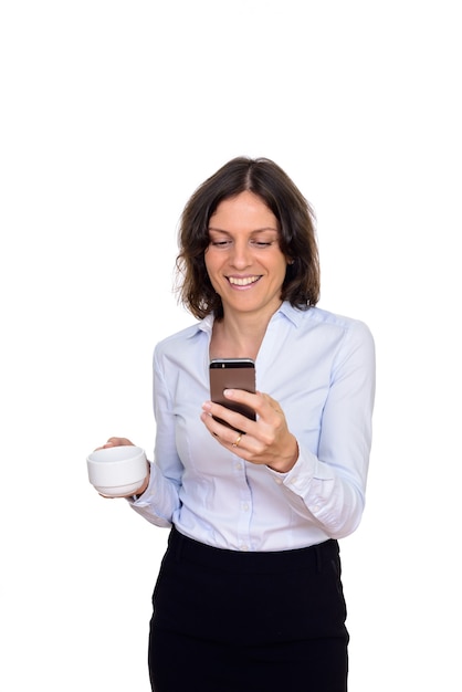 Photo de Studio de femme heureuse à l'aide de téléphone mobile tout en tenant une tasse de café isolé sur fond blanc