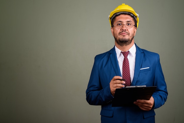 Photo de Studio d'homme d'affaires barbu portant costume et casque contre coloré