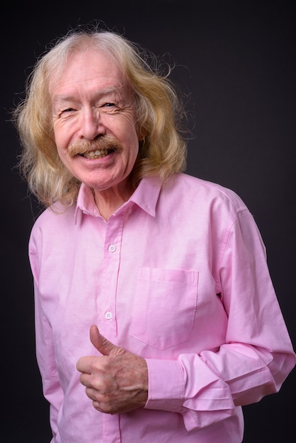 Photo de Studio d'homme d'affaires senior avec moustache portant une chemise rose sur fond gris