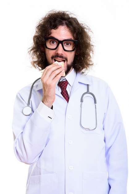 Photo de Studio d'homme heureux médecin souriant et mangeant un sandwich