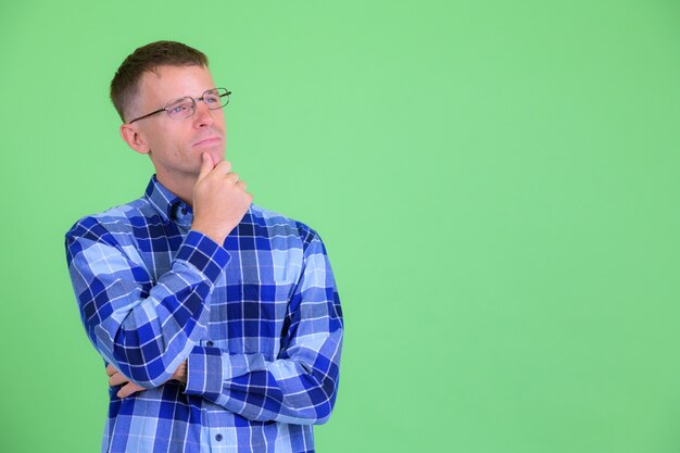 Photo de Studio d'homme hipster portant des lunettes sur fond vert