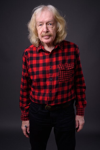 Photo de Studio d'un homme senior avec moustache portant une chemise à carreaux rouge sur fond gris