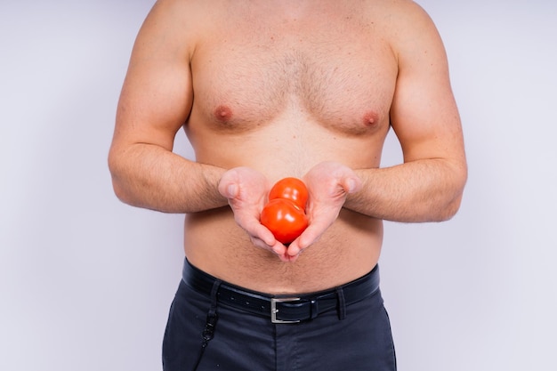 Photo de studio isolée complète d'un jeune homme nu avec des sous-vêtements et des tomates