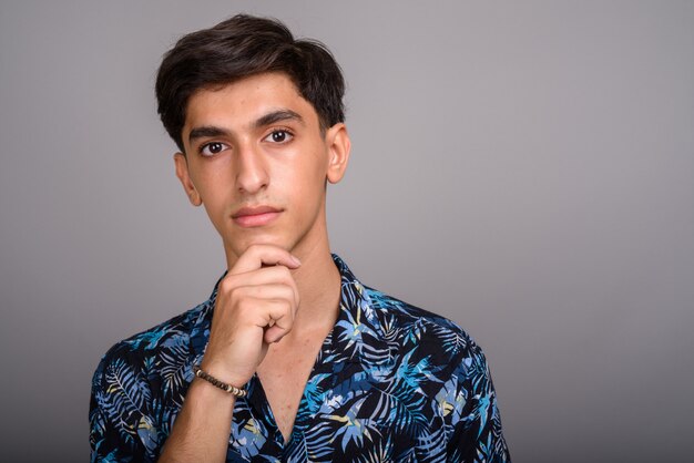 Photo de Studio de jeune adolescent persan beau portant chemise hawaïenne sur fond gris