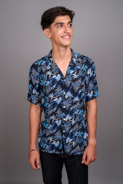 Photo de Studio de jeune adolescent persan beau portant chemise hawaïenne sur fond gris