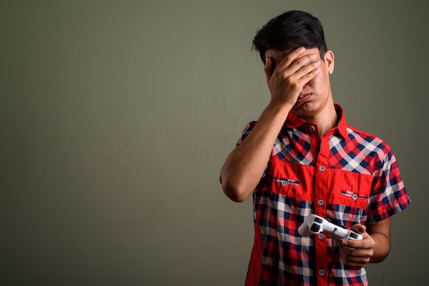 Photo de Studio de jeune adolescent vêtu d'une chemise à carreaux rouge contre coloré