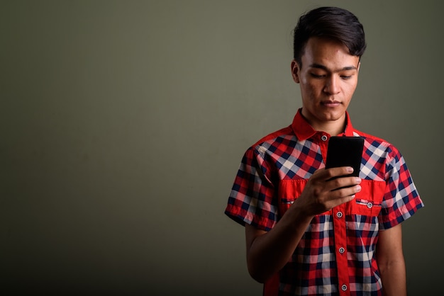 Photo de Studio de jeune adolescent vêtu d'une chemise à carreaux rouge contre coloré