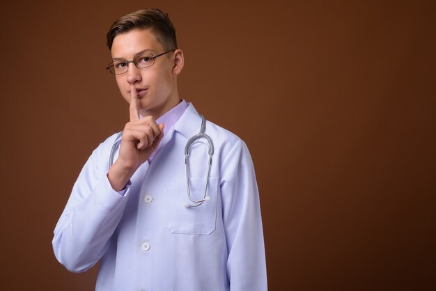 Photo de Studio de jeune beau médecin sur fond marron