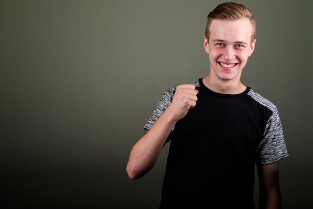 Photo de Studio de jeune bel homme aux cheveux blonds sur fond coloré