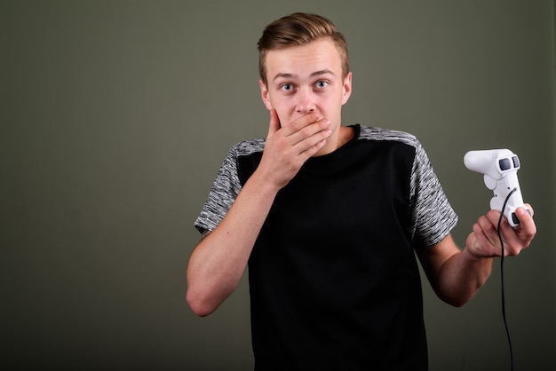 Photo de Studio de jeune bel homme aux cheveux blonds sur fond coloré