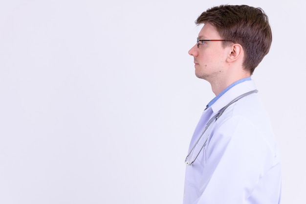 Photo de Studio de jeune bel homme médecin avec des lunettes contre le blanc