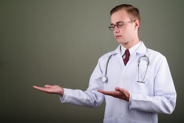 Photo de Studio de jeune bel homme médecin portant des lunettes sur fond coloré