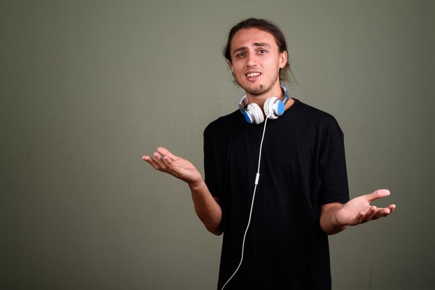 Photo de Studio de jeune bel homme portant des écouteurs sur fond coloré