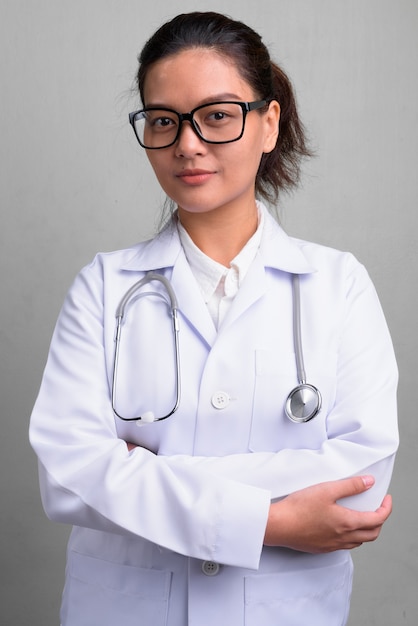 Photo de Studio de jeune belle femme asiatique médecin portant des lunettes contre le blanc