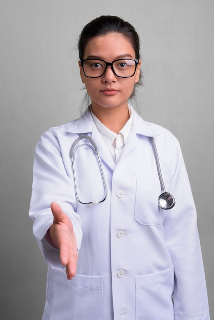 Photo de Studio de jeune belle femme asiatique médecin portant des lunettes contre le blanc