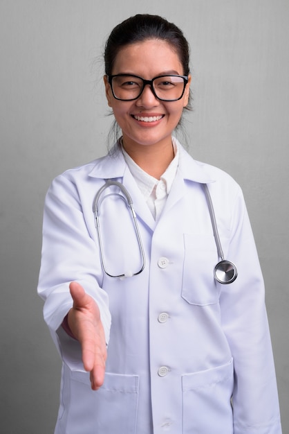 Photo de Studio de jeune belle femme asiatique médecin portant des lunettes contre le blanc