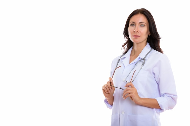 Photo de Studio de jeune belle femme médecin pensant tout en tenant des lunettes