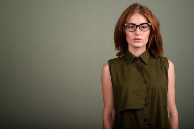 Photo de Studio de jeune femme portant haut sans manches vert et lunettes sur fond coloré