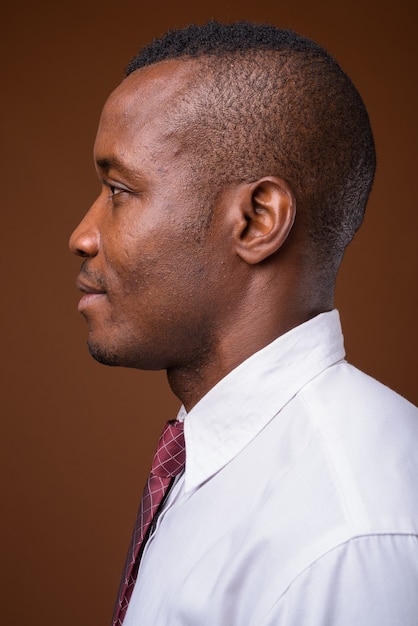Photo de Studio de jeune homme d'affaires africain sur fond marron