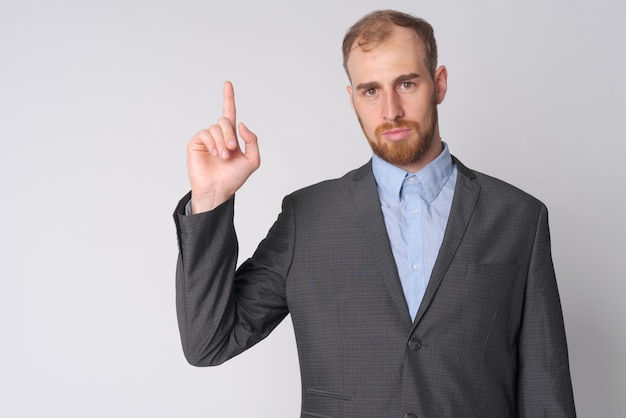 Photo de Studio de jeune homme d'affaires barbu portant costume contre blanc