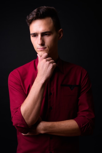 Photo de Studio de jeune homme d'affaires beau en chemise rouge sur fond noir