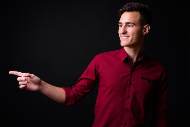 Photo de Studio de jeune homme d'affaires beau en chemise rouge sur fond noir