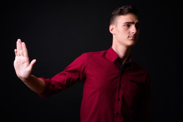 Photo photo de studio de jeune homme d'affaires beau en chemise rouge sur fond noir